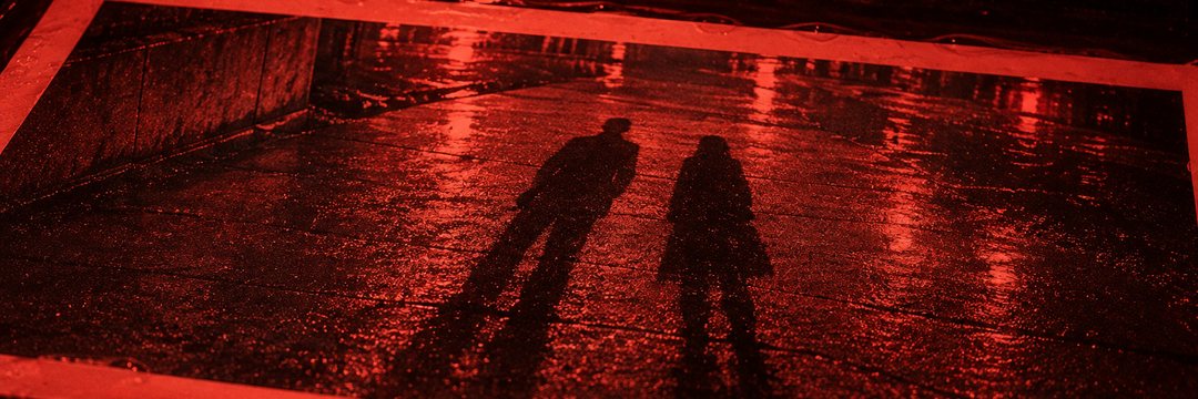 細い横の帯の寄り。赤い灯の下の印画紙。夜の地面に、並んで伸びる2つの人の影。