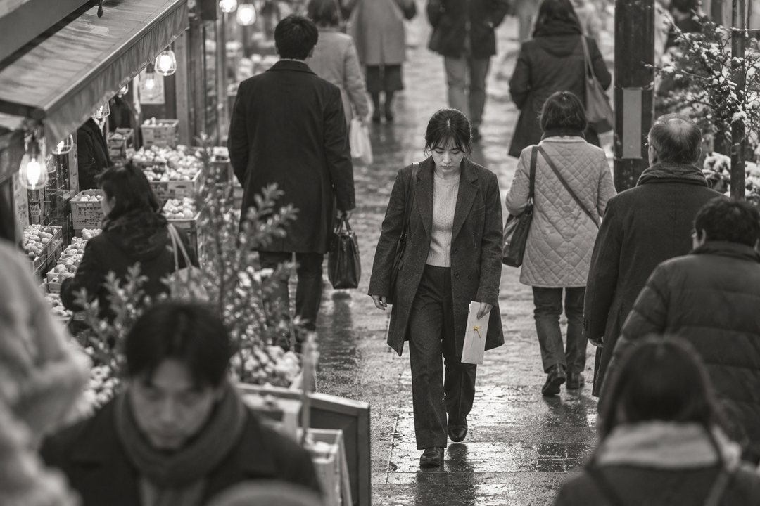 夕方の商店街を高い所から。人の流れの中を、封筒を下げてうつむいて歩く真琴が小さく見える。